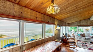 Un intérieur en bois avec de grandes fenêtres, un fauteuil à bascule, un banc et un canapé.