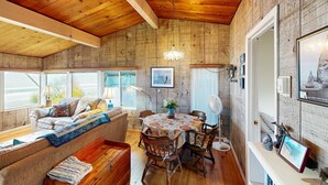 Une pièce chaleureuse avec un plafond en bois, un canapé, une table à manger avec des chaises et un ventilateur.