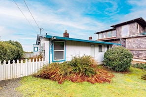 A single-story house with a blue door, a small porch, and a white picket fence. - Comfy oceanfront home three blocks to the beach with amazing views - dogs OK (Arch Cape)