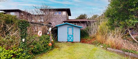 Une maison avec une porte de garage bleue, une cour couverte d’herbe et une clôture en bois.