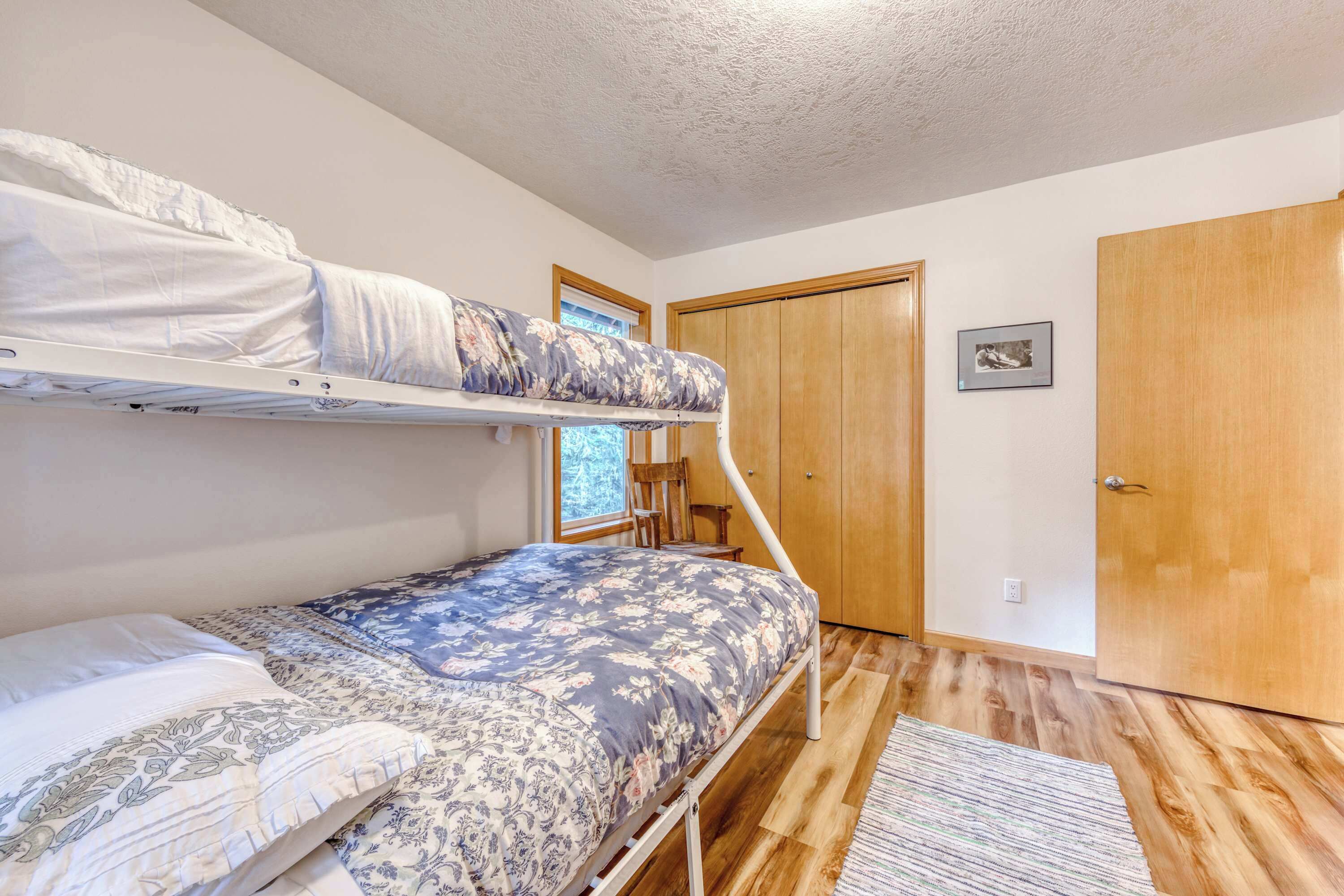 Een kamer met een stapelbed, een houten deur en een raam.