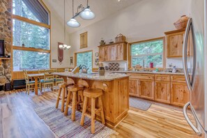 Una cocina amplia con armarios de madera, una isla grande con taburetes y un refrigerador.