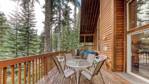 A wooden deck with a glass door, surrounded by tall trees. - Mountain-view house near skiing with a great kitchen & private hot tub (Government Camp)