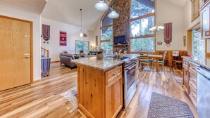 A spacious kitchen with wooden cabinets, a large island, and a stone accent wall. - Mountain-view house near skiing with a great kitchen & private hot tub (Government Camp)