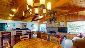 Un intérieur en bois comprenant une table à manger, des chaises, un canapé, un téléviseur et une cheminée.