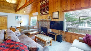 Un salon chaleureux avec une cheminée, des murs en bois, un canapé, une table basse et un téléviseur.