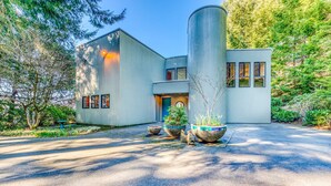 A modern building with a curved facade, large windows, and a central entrance. - Mid-century home with floor-to-ceiling windows & great views (Coos Bay)
