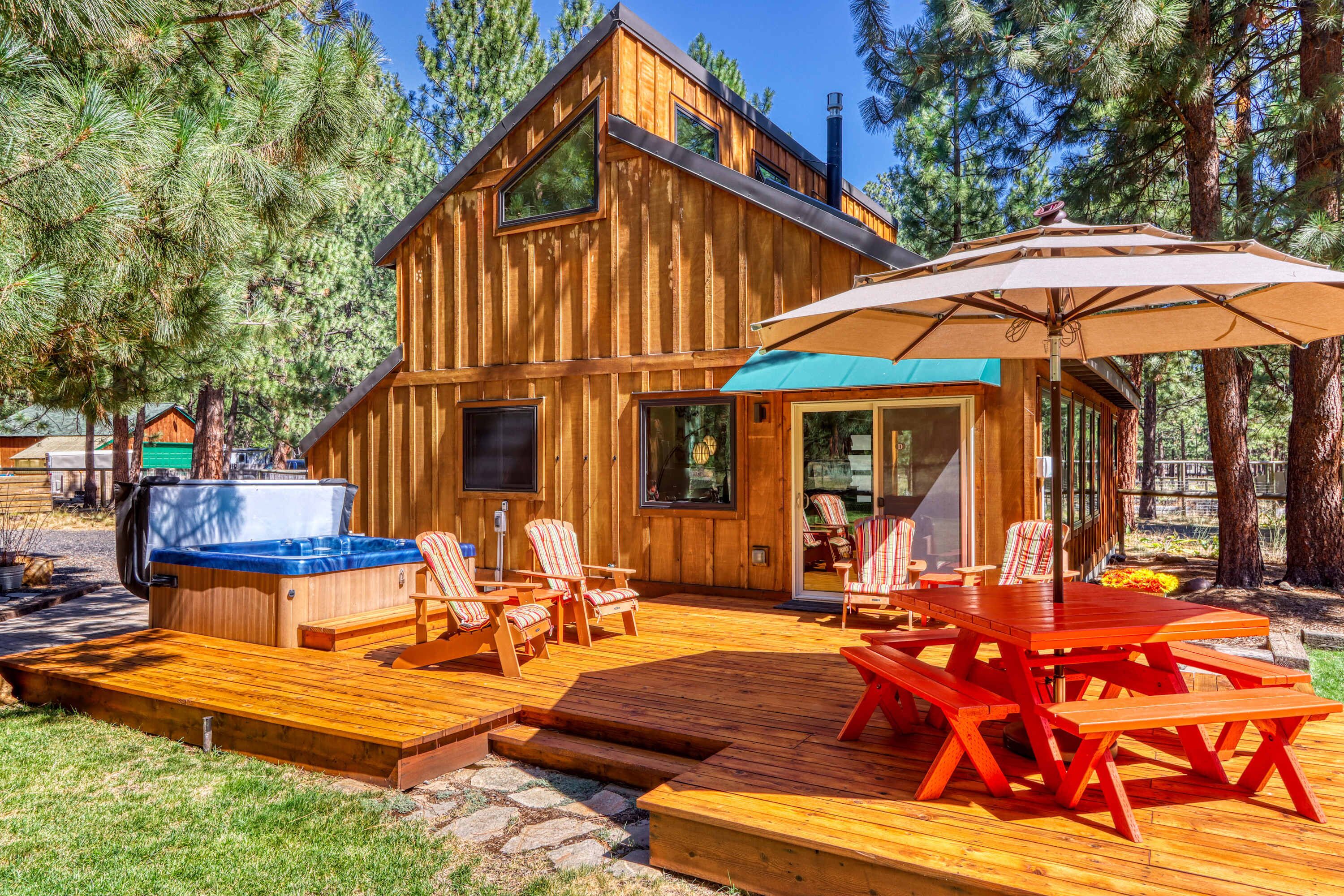 Une cabane en bois dotée d’une terrasse, d’un espace salon extérieur et d’un jacuzzi.