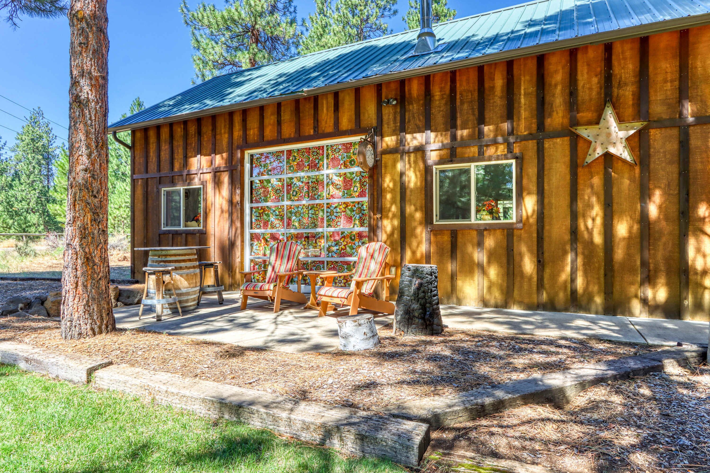 A rustic wooden cabin with a large window, outdoor seating, and a star decoration.