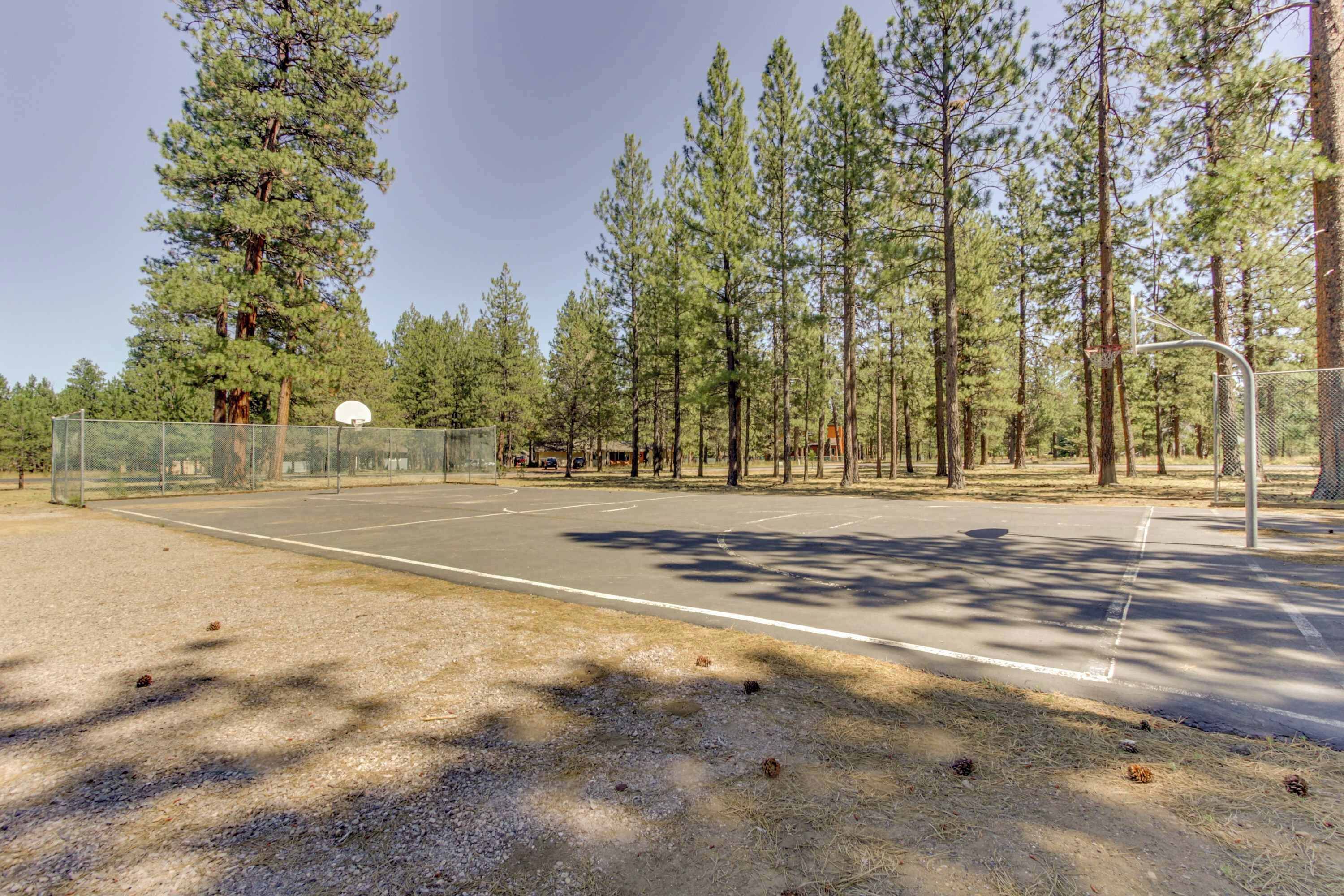 An outdoor basketball court surrounded by trees.