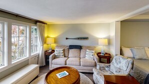 A living room with a beige sofa, a patterned armchair, a wooden coffee table, and a lamp.