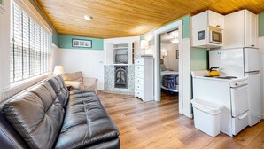 Un espacio habitable compacto con kitchenette, chimenea, sofá y comedor.