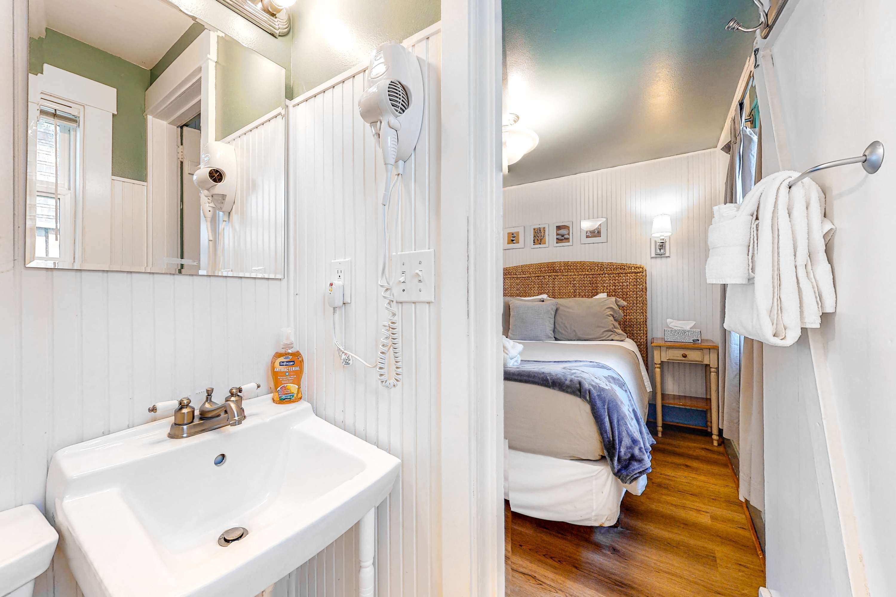 A bathroom with a sink, a hairdryer, and a mirror.