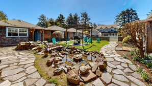 Un patio de piedra con un estanque, mobiliario de exterior y una pérgola.