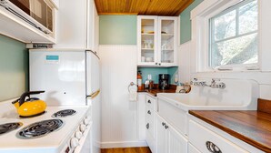 Una cocina con armarios blancos, un hervidor amarillo, un refrigerador blanco y una encimera de madera.