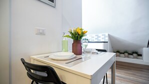 Een eettafel met borden, bestek, een fles en een vaas met bloemen.