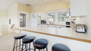 Una cucina moderna con mobili bianchi, una grande isola con sgabelli e un tostapane.