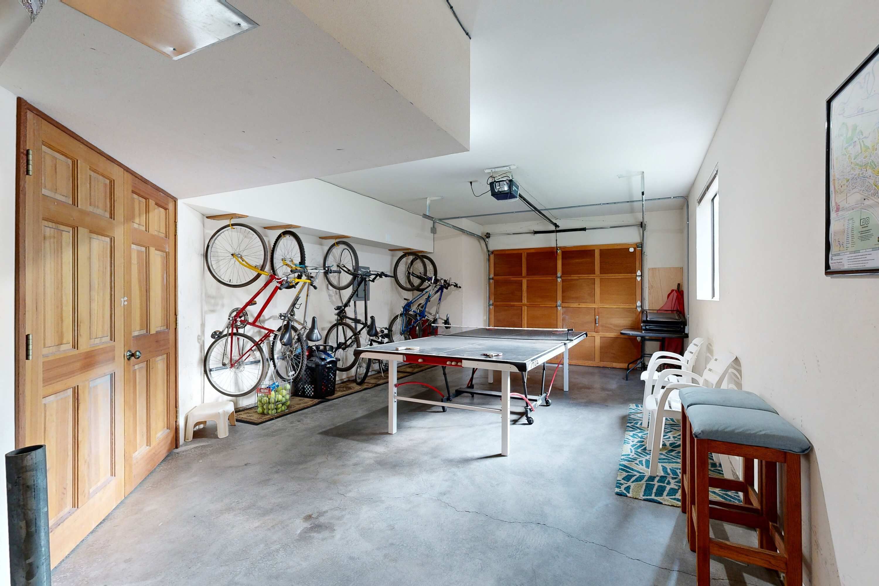 A garage with a ping pong table, bicycles, and a wooden door.