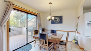 Et spiseområde med et bord, stole, en lysekrone, en kost og et køleskab.