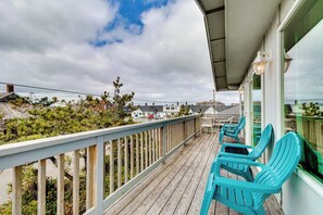 Une terrasse en bois, dotée de chaises turquoise et d’une balustrade donnant sur un quartier résidentiel.