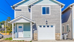 Une maison à deux étages avec un garage, un porche à l’avant et des fondations en pierre.