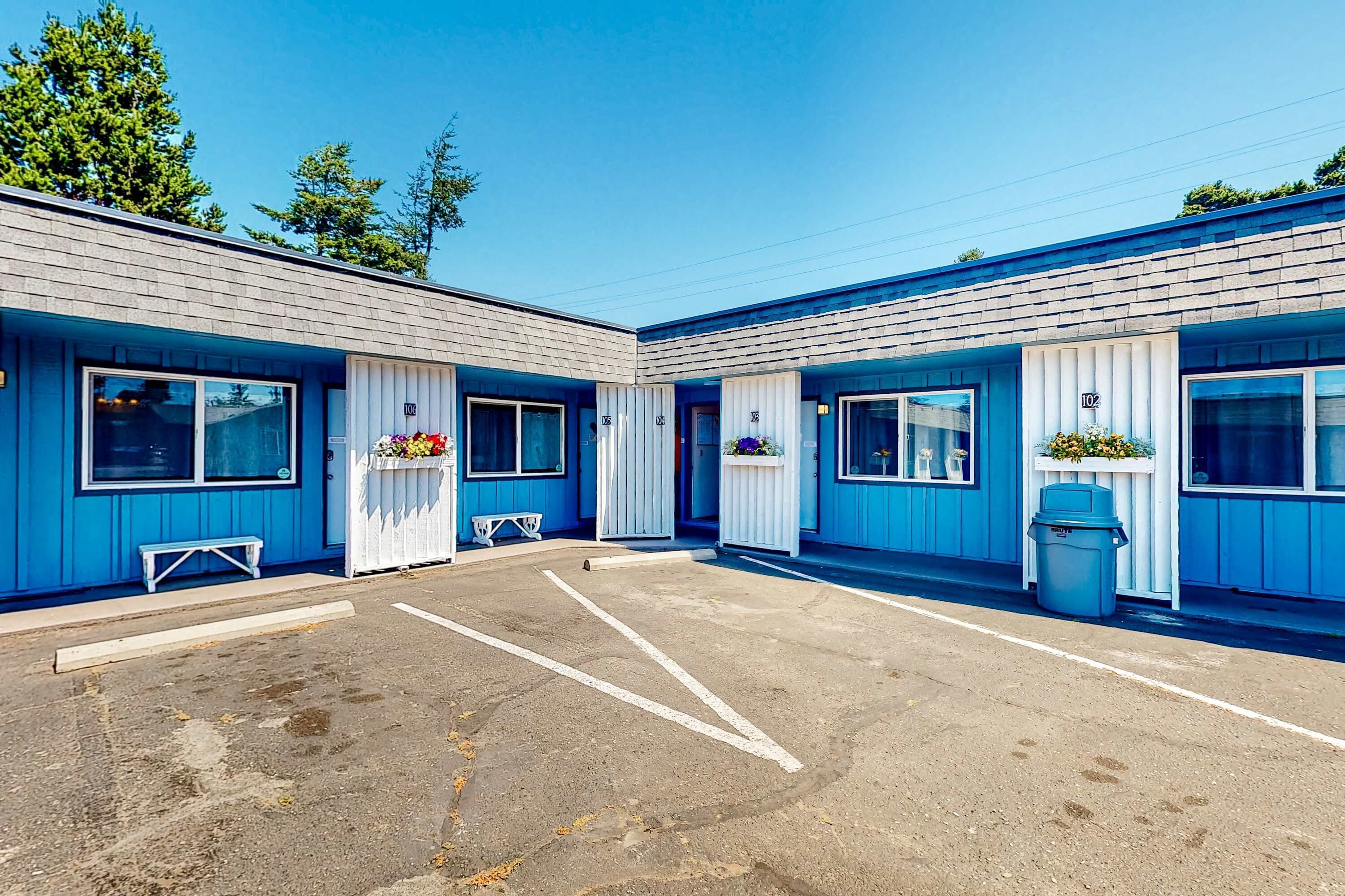 Un motel con edificios de dos pisos, un estacionamiento y una fila de ventanas.