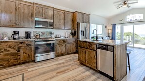 Une cuisine moderne avec des armoires en bois, des appareils en acier inoxydable et un grand îlot central.