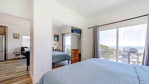 Une chambre à coucher avec un lit, une commode, un miroir et un balcon offrant une vue.
