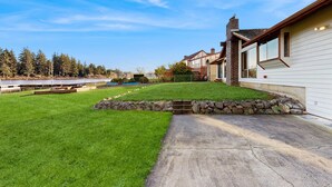 Una propiedad residencial con un césped bien cuidado, un muro de contención de piedra y un camino de acceso que lleva a una casa con chimenea.