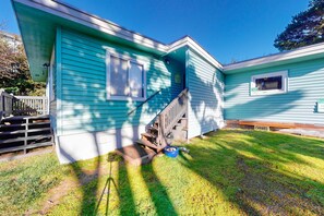 A two-story house with a front porch, a small front yard, and a visible staircase leading to the second floor. - Dog-friendly rustic house near ocean and golf with washer/dryer & gas grill (Florence)