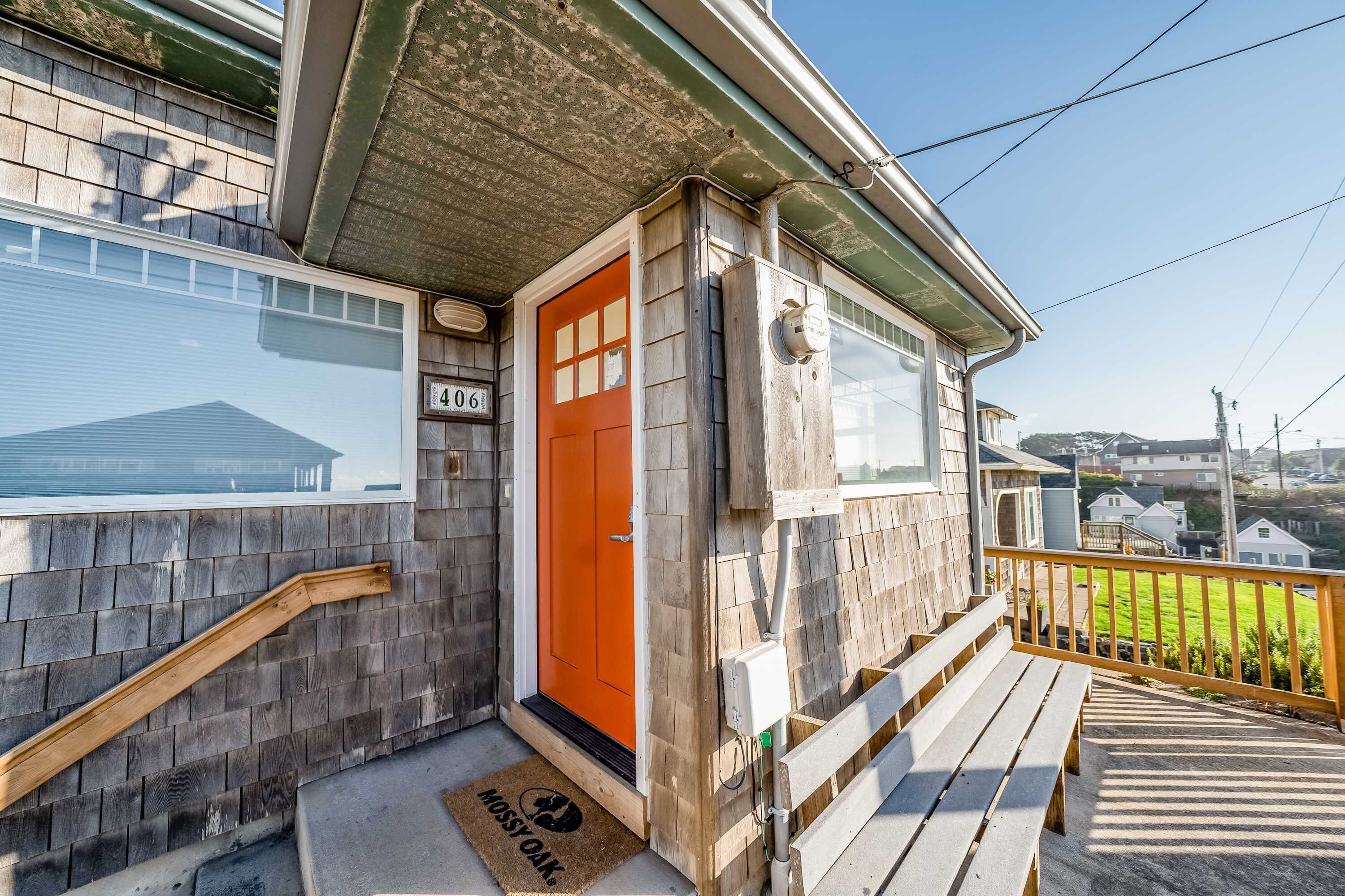 A house with a wooden exterior, a red door, and a number '406' on the wall.