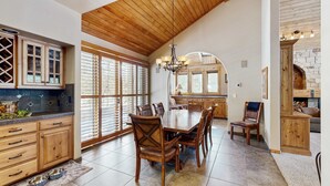 A spacious kitchen with wooden cabinets, a dining table with chairs, and a stone fireplace. - Spacious Family Home with Hot Tub, AC, Garage Gym & SHARC Amenities (Sunriver)