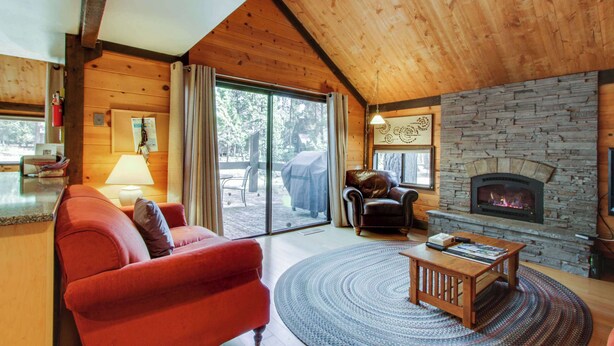 Ein gem ütliches Wohnzimmer mit Kamin, einem roten Sofa, einem Holztisch und einer Steinwand.