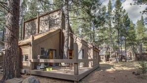 Eine Hütte mit einer Terrasse, umgeben von Bäumen.