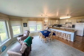 A spacious kitchen with a central island, wooden chairs, and a dining table.