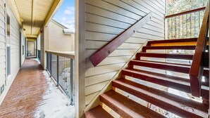 Un escalier en bois avec une rampe métallique menant à un niveau supérieur.