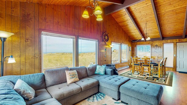 Een gezellig interieur van een chalet met een hoekbank, een pouf, een eettafel en stoelen.