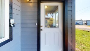 A white door with a glass panel, a mailbox, and a wall-mounted light fixture. - Beautifully renovated home across street from beach access - dogs welcome (Waldport)