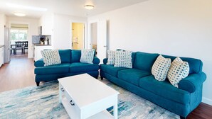 A modern living room with a teal sofa set, white coffee table, and patterned pillows. - Beautifully renovated home across street from beach access - dogs welcome (Waldport)