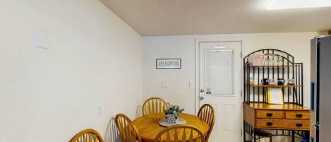 A dining area with a round table and chairs, a door with a sign, and a metal rack with items.