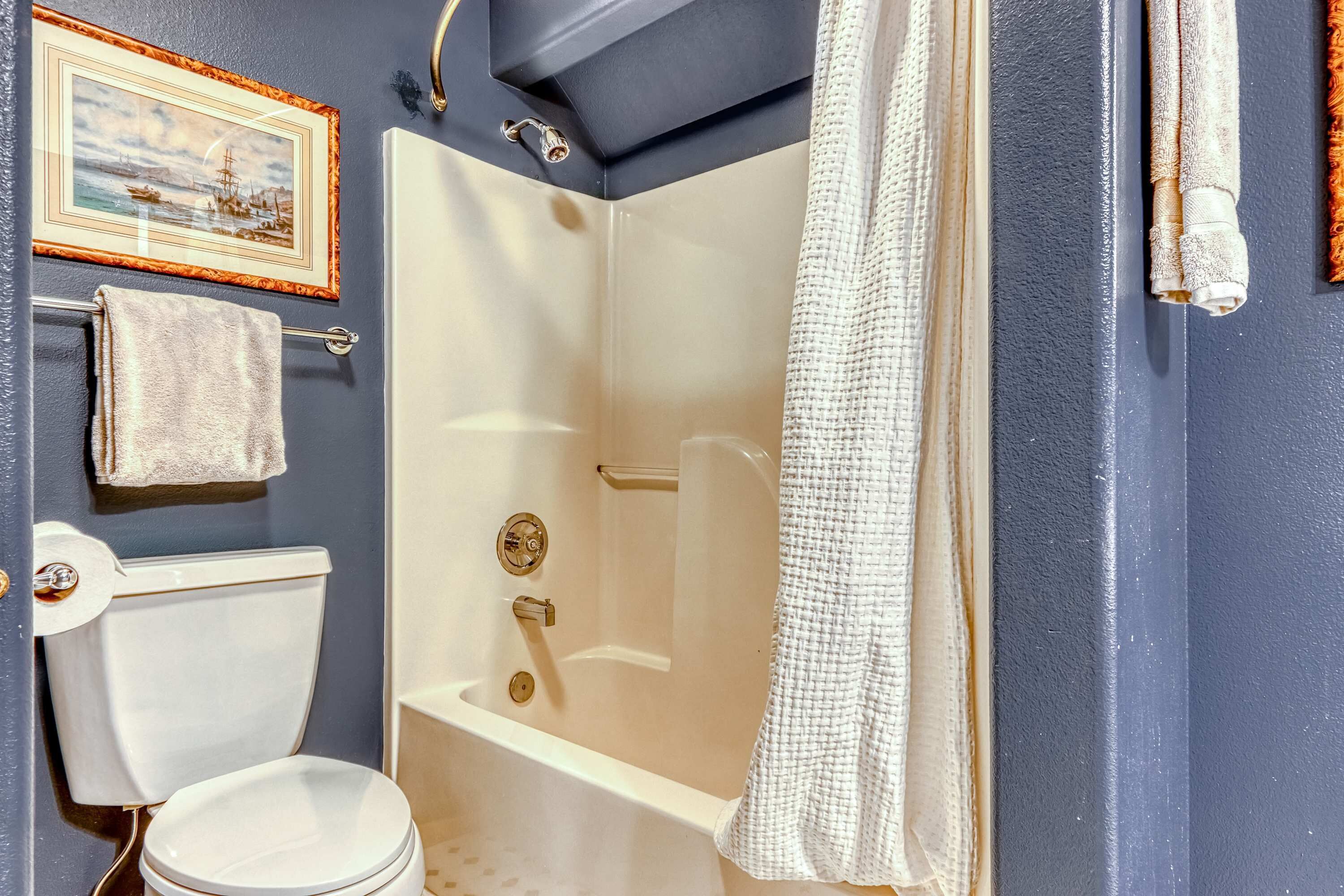 Ein Badezimmer mit Badewanne, Toilette und einem gerahmten Bild an der Wand.