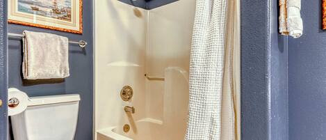 Ein Badezimmer mit Badewanne, Toilette und einem gerahmten Bild an der Wand.