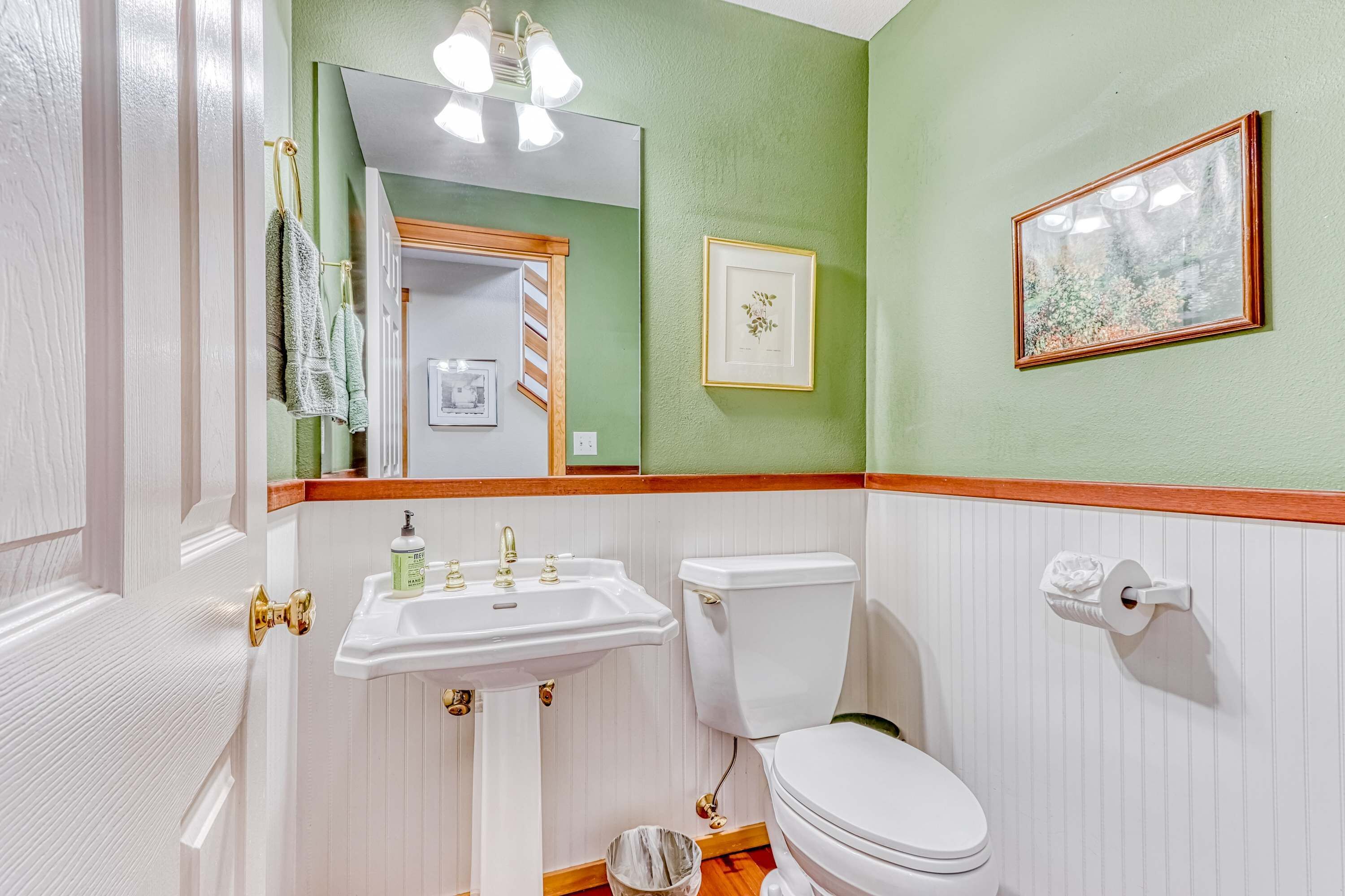 A bathroom with a sink, toilet, and framed picture on the wall.
