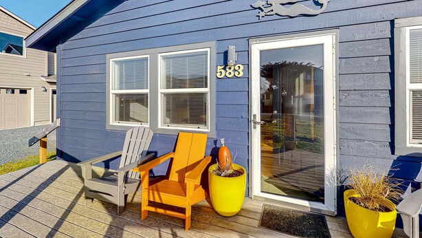 Een blauw huis met nummer 583, een houten stoel en een gele plantenbak op de veranda.
