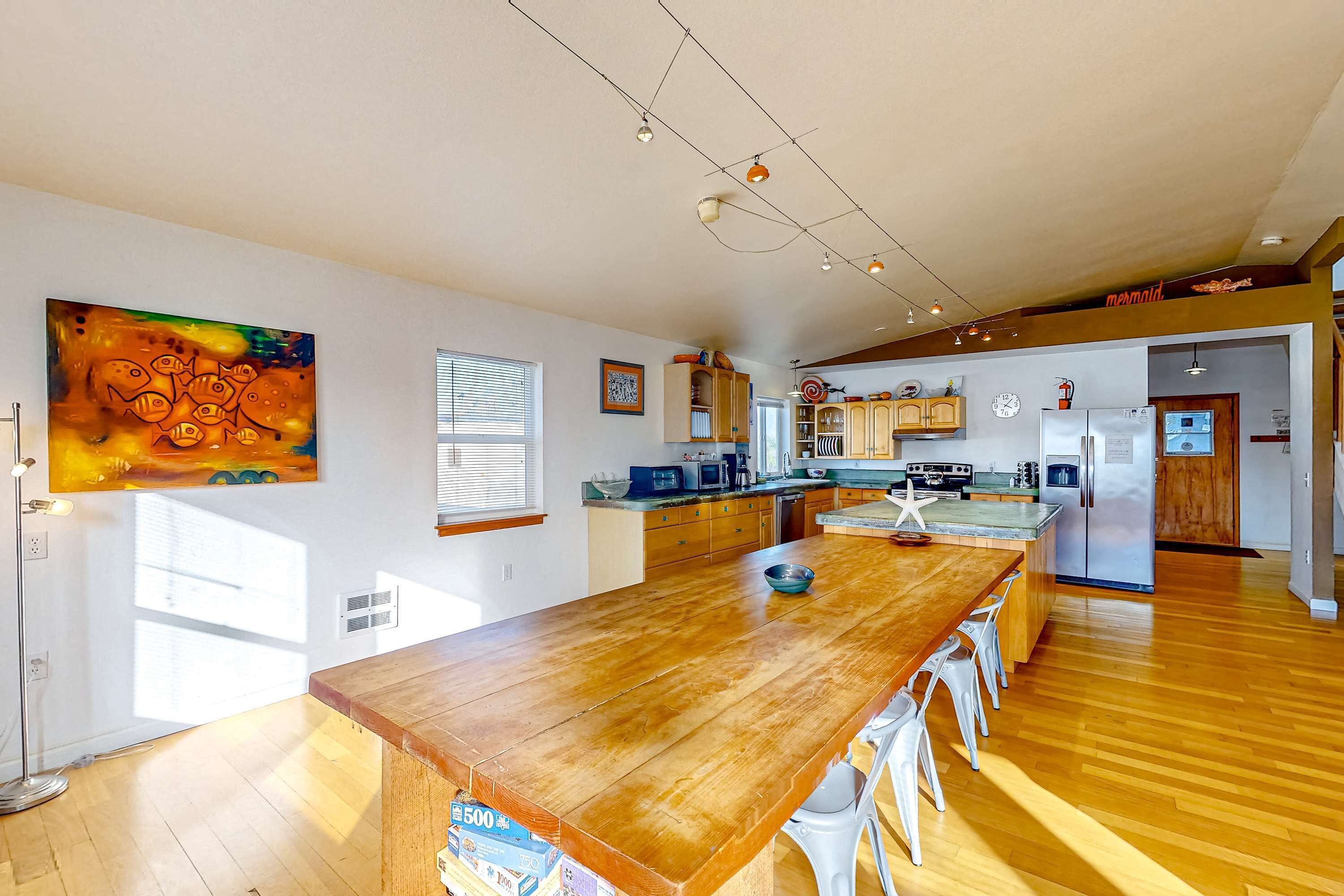 Une cuisine spacieuse avec un îlot central en bois, des appareils modernes et un grand tableau accroché au mur.