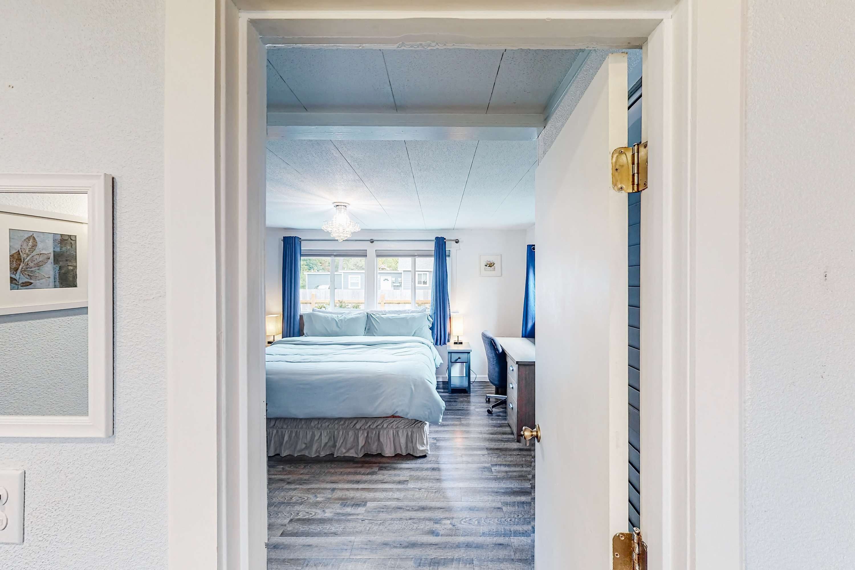 Un dormitorio con cama, escritorio, silla, mesita de noche y candelabro.