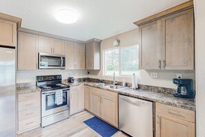 A kitchen with wooden cabinets, a stainless steel stove, a microwave, and a dishwasher. - Home near the ocean with wood stove, large yard, washer&dryer, streaming, patio (Coos Bay)
