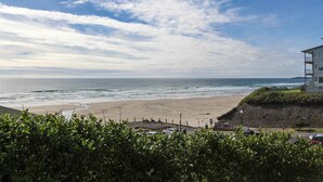 A beach view with a building on the right, a clear sky, and a sandy shore. - Ocean View Home with Free WiFi and Cable and a Full Kitchen - One Dog is Welcome (Newport)