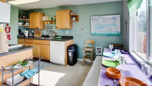 A kitchen with wooden cabinets, a dishwasher, and a dining table set with plates and glasses. - Ocean View Home with Free WiFi and Cable and a Full Kitchen - One Dog is Welcome (Newport)