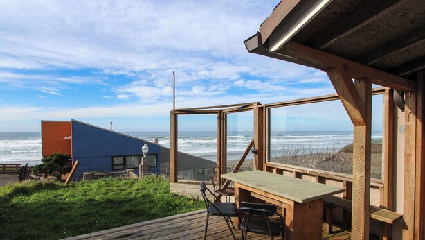 A wooden deck with a table and chairs overlooking the ocean. - Ocean View Home with Free WiFi and Cable and a Full Kitchen - One Dog is Welcome (Newport)